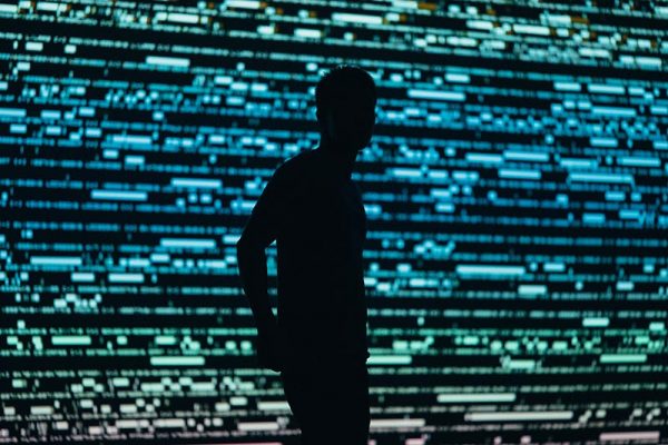Anonymous figure in front of digital wall of data
